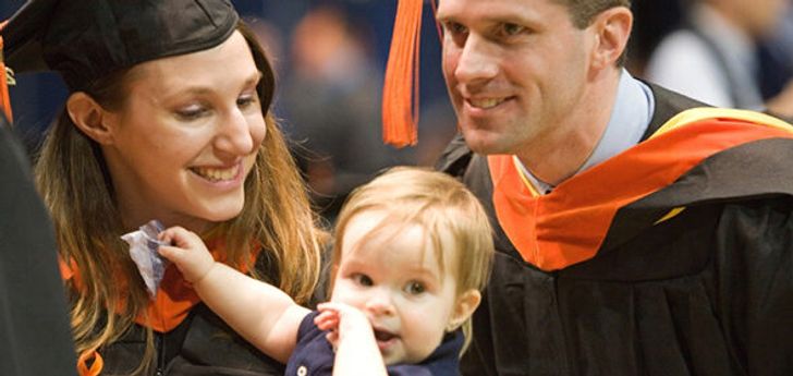 A couple in caps and gowns with a small child