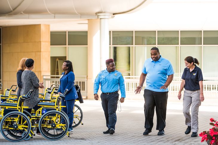 Staff talking near outdoor wheelchair storage at Michigan Medicine facility