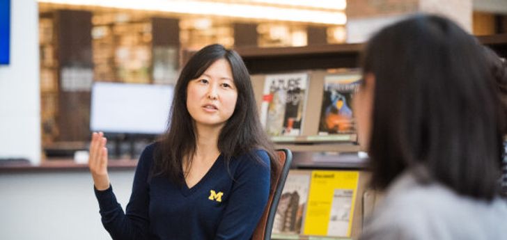 A woman wearing a U-M sweater having a conversation in a library